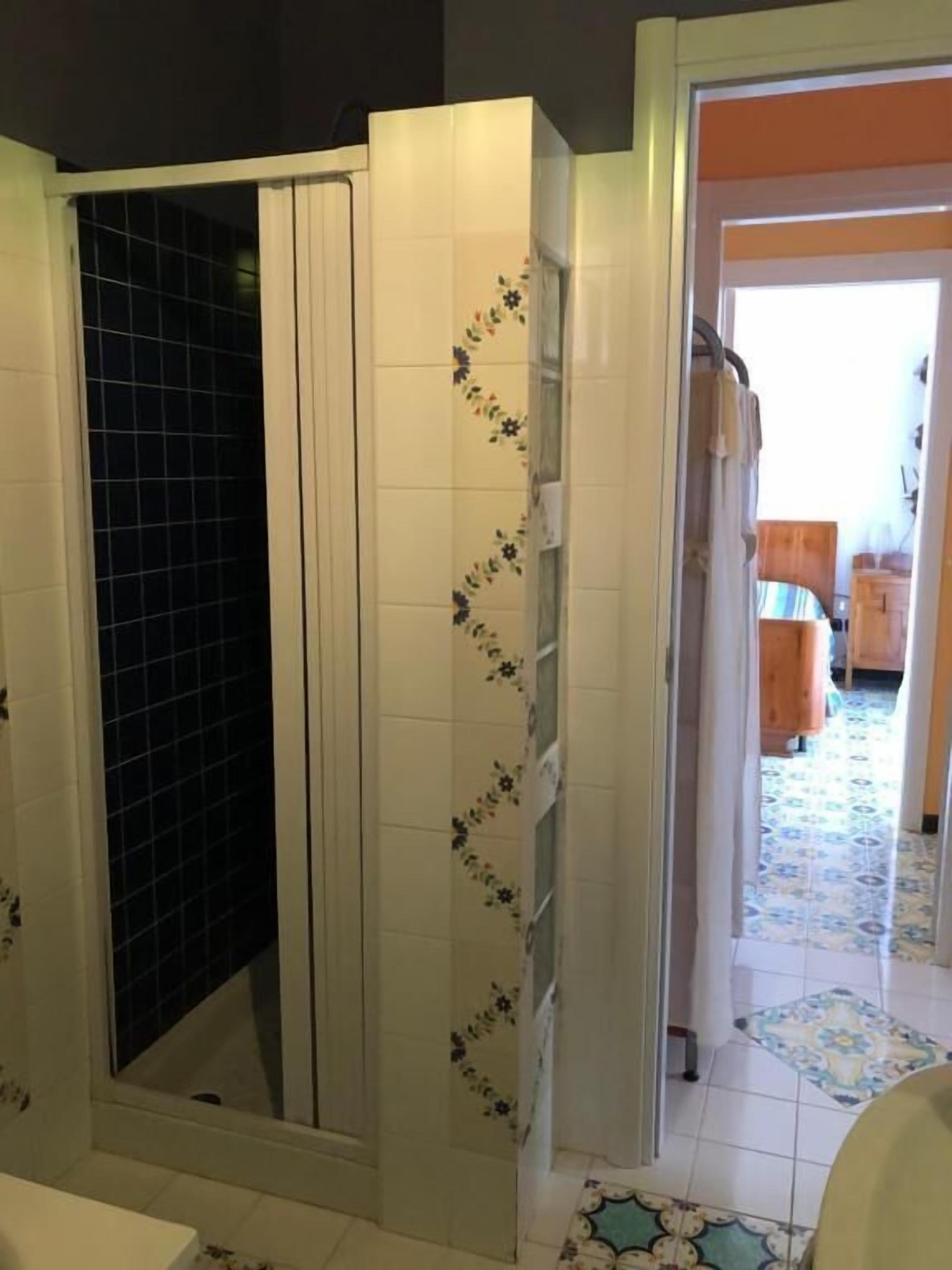 Een badkamer met een douchecabine, betegelde wanden en een patroon vloer.