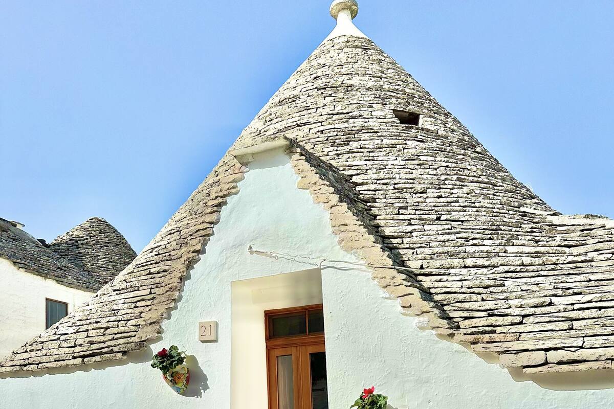 A traditional stone-roofed building with a wooden door and two flower pots on the walls.