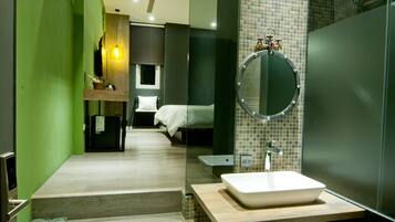 Un baño moderno con un espejo grande, un lavamanos y una zona de ducha.