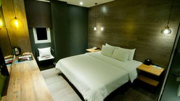 A modern bedroom with a wooden headboard, a large bed, bedside tables, and a desk with a chair.