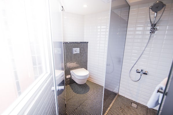 A modern bathroom with a toilet, shower, and a glass partition. - Huwei Hotel (Huwei)