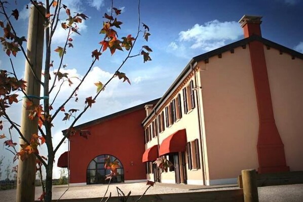 A building with a red facade and a beige upper section, featuring a large arched entrance and a chimney. - Agriturismo Ronchetrin (Gazzo Veronese)