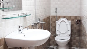 Une salle de bain avec un lavabo blanc, des toilettes, une douche et un miroir.