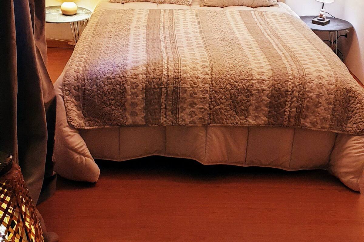 A cozy bedroom with a bed, two bedside tables, and a lamp.