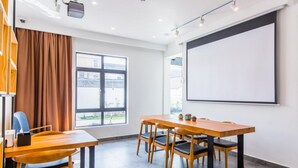 A modern meeting room with a large table, chairs, a projector screen, and a window with curtains. - Mishe TEN Boutique Inn (Shanghai)