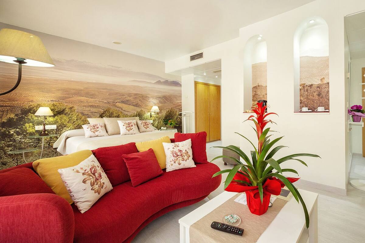 A modern living room with a red sofa, a coffee table with a remote control, and a large wall mural.