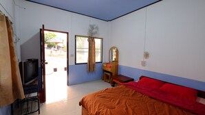 A bedroom with a bed, a television, a desk, and a window.