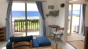 Una habitación con vista al océano, un sofá azul, una mesa de madera y una silla.