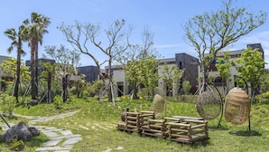 Ein Garten mit einem Kiesweg, hölzernen Bänken und Hängesesseln.