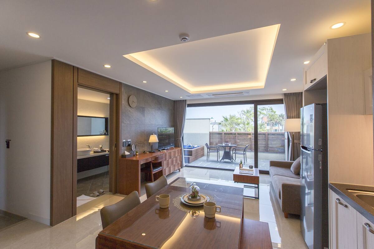 Une chambre d’hôtel moderne dotée d’un coin repas, d’une kitchenette et d’un balcon avec mobilier d’extérieur.