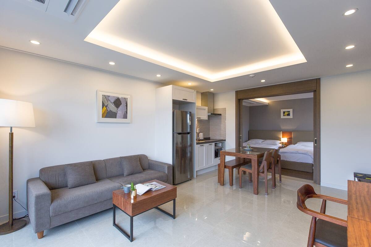 Une chambre d’hôtel moderne équipée d’un canapé, d’une table à manger, de chaises, d’une kitchenette et d’un lit.