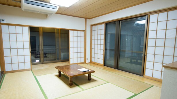 Una habitación japonesa tradicional con suelo de tatami, puertas correderas y una mesa de madera.