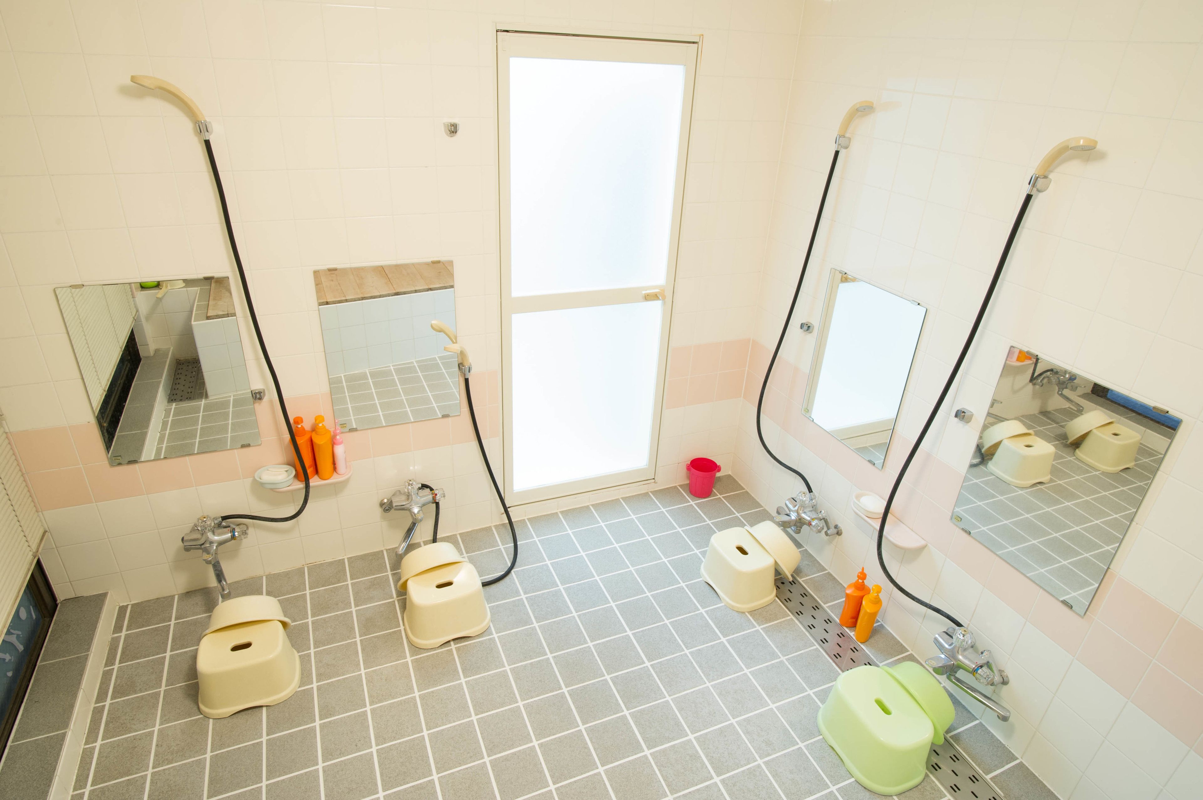 A bathroom with three toilets, a sink, and a mirror.