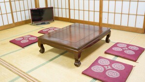 Una habitación con esteras de tatami, una mesa de madera y cojines.