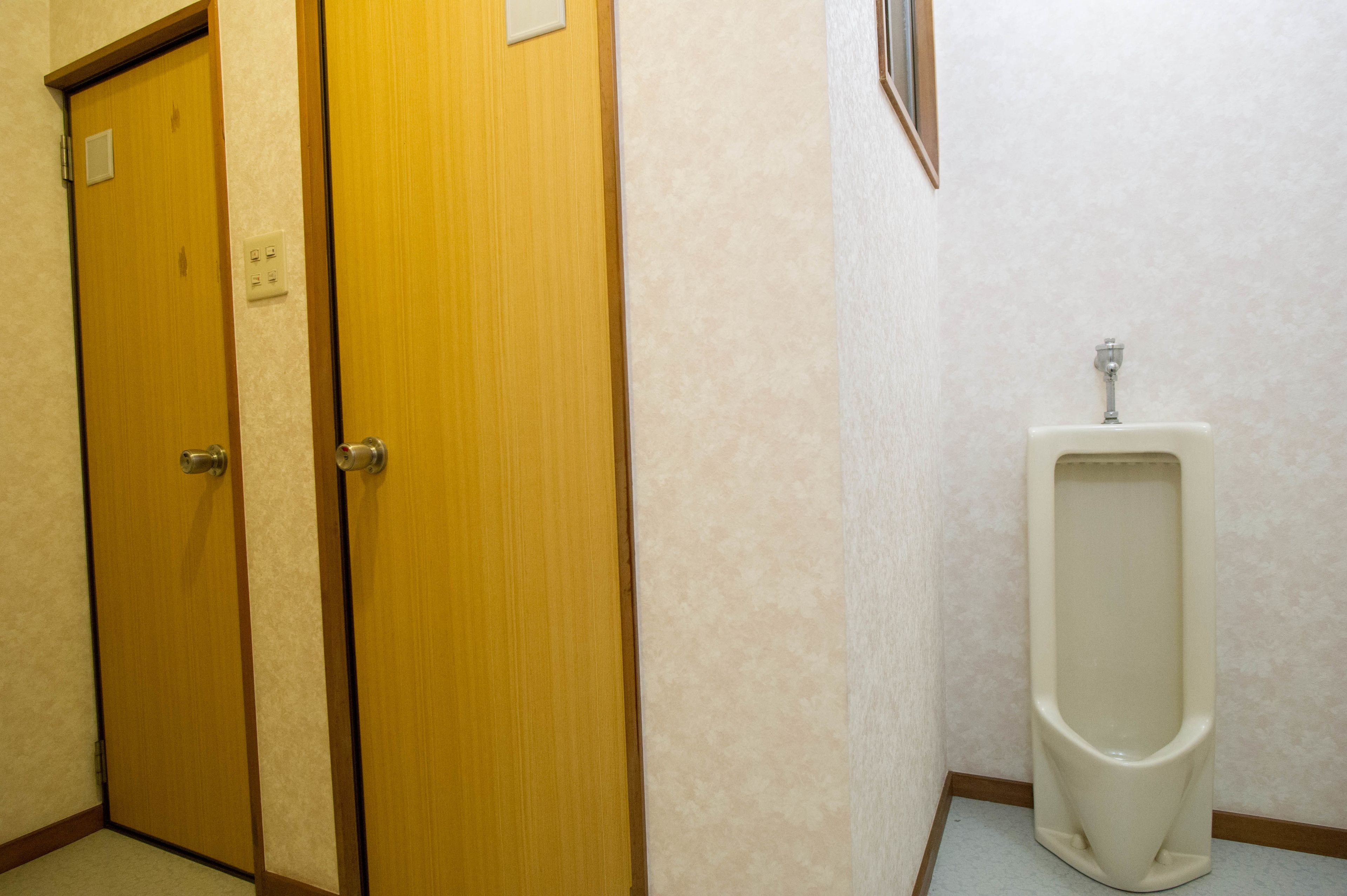 A men's restroom with two wooden doors and a urinal.