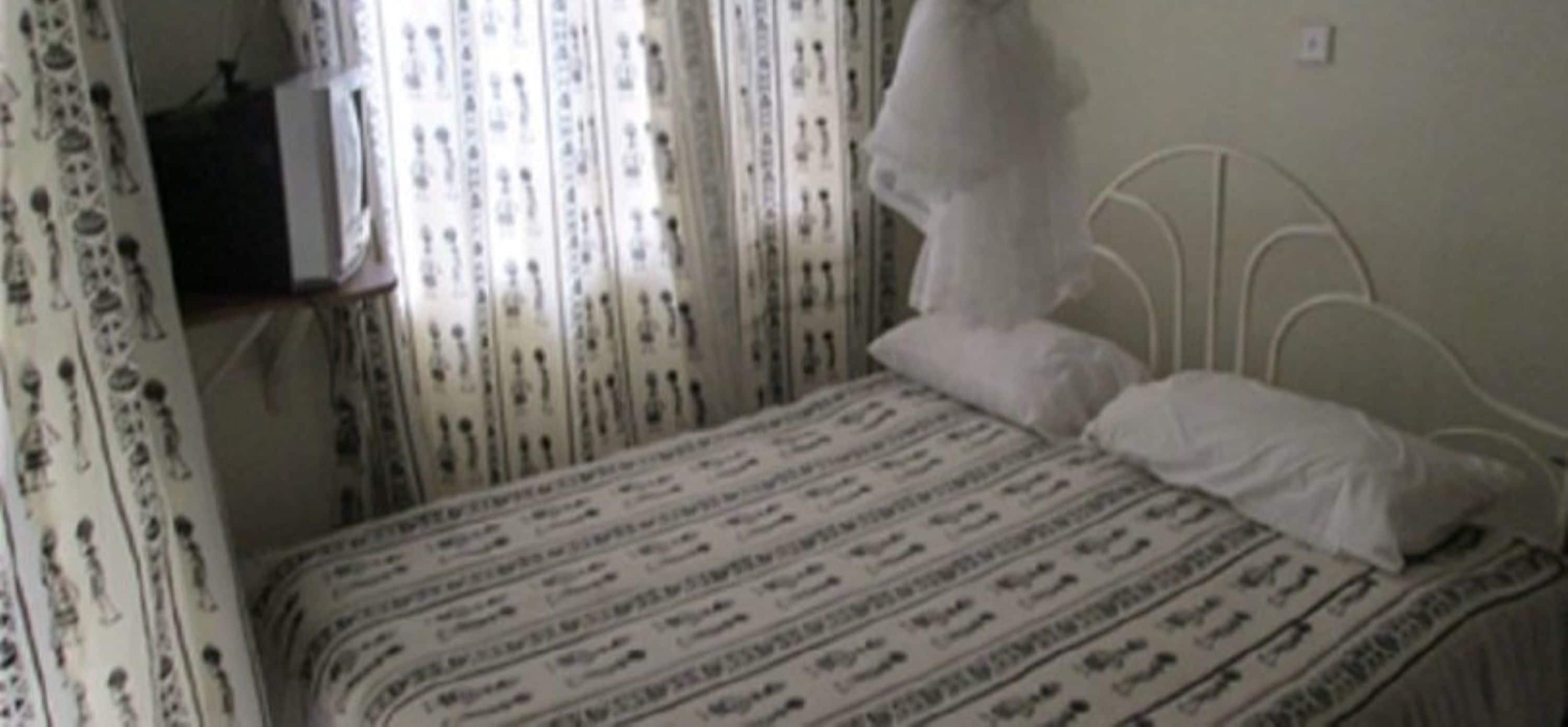 A bedroom with a bed, curtains, and a wall socket.