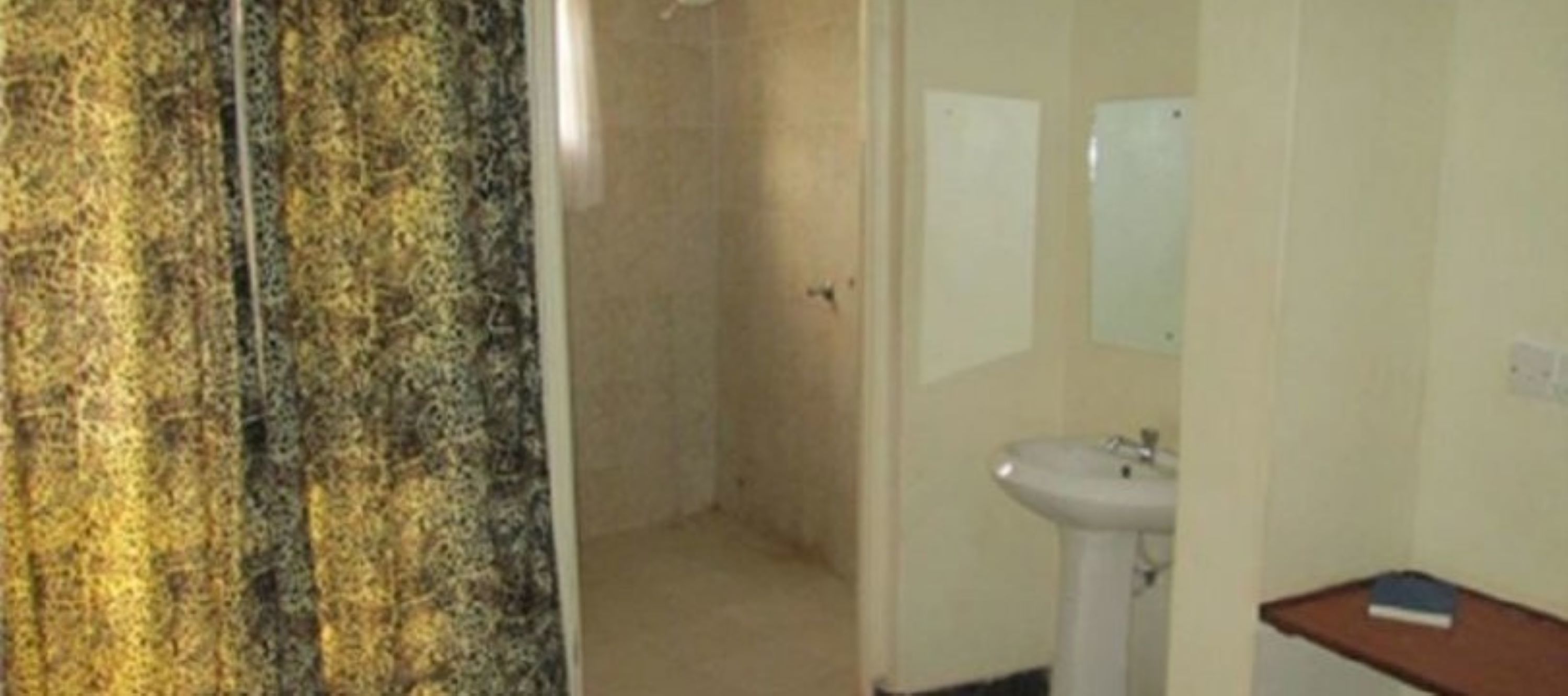 Un baño con lavamanos, espejo y zona de ducha.