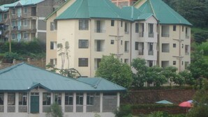 A multi-story building with a green roof, surrounded by greenery and other buildings. - Fortune Green Hotel (Murang'a)