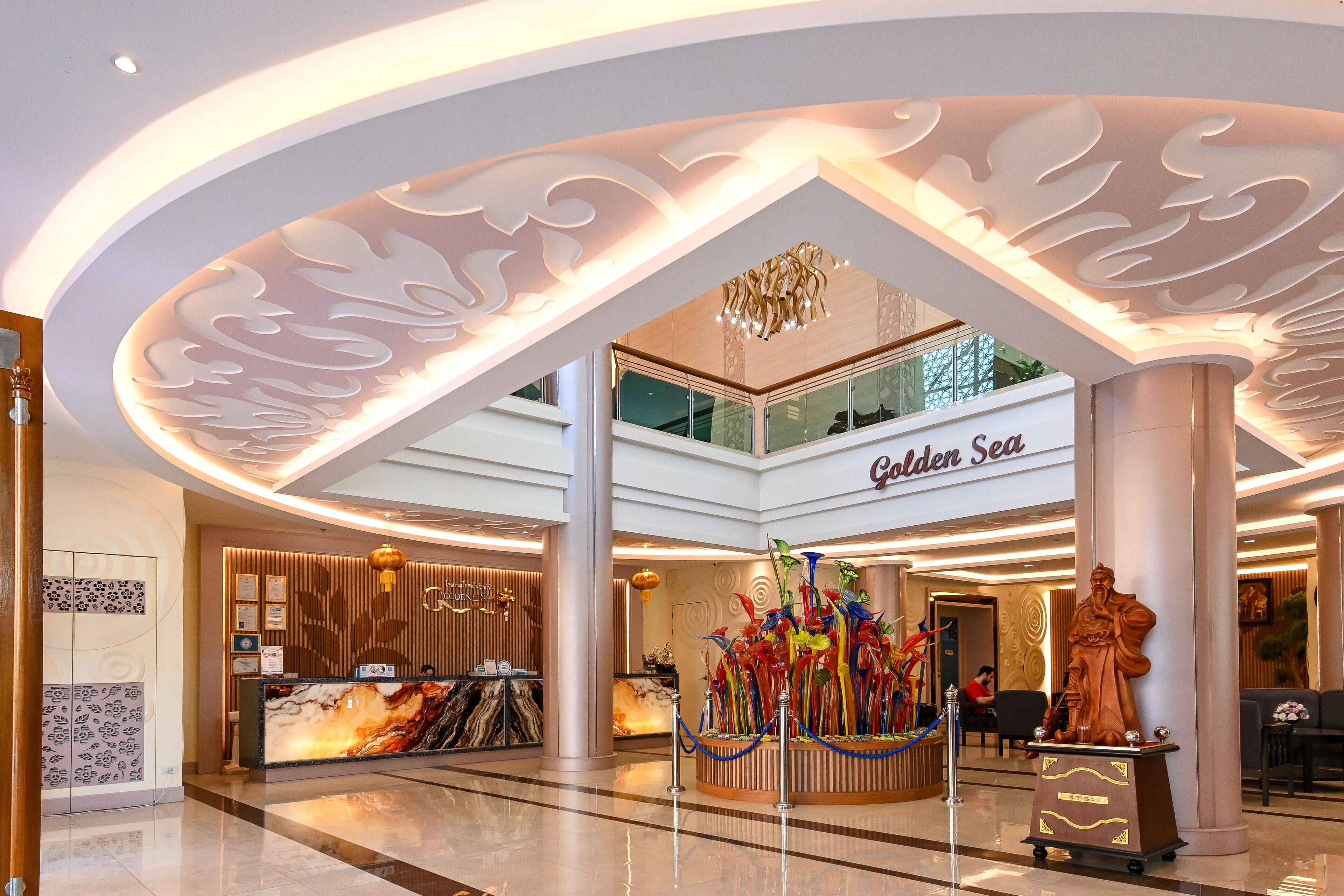 A hotel lobby with a reception desk, a statue, and a glass sculpture.