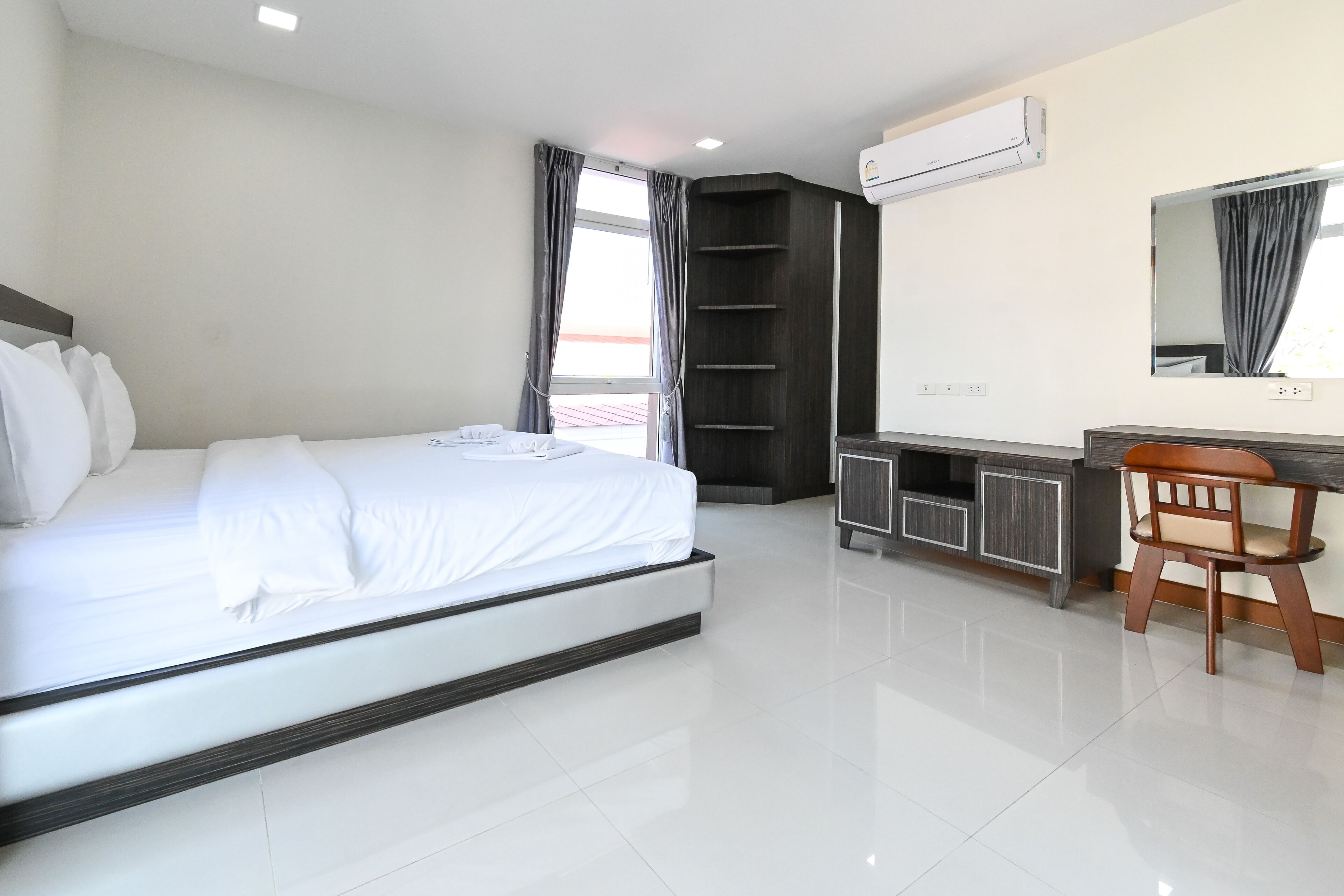 A modern hotel room with a large bed, a desk, and a chair.