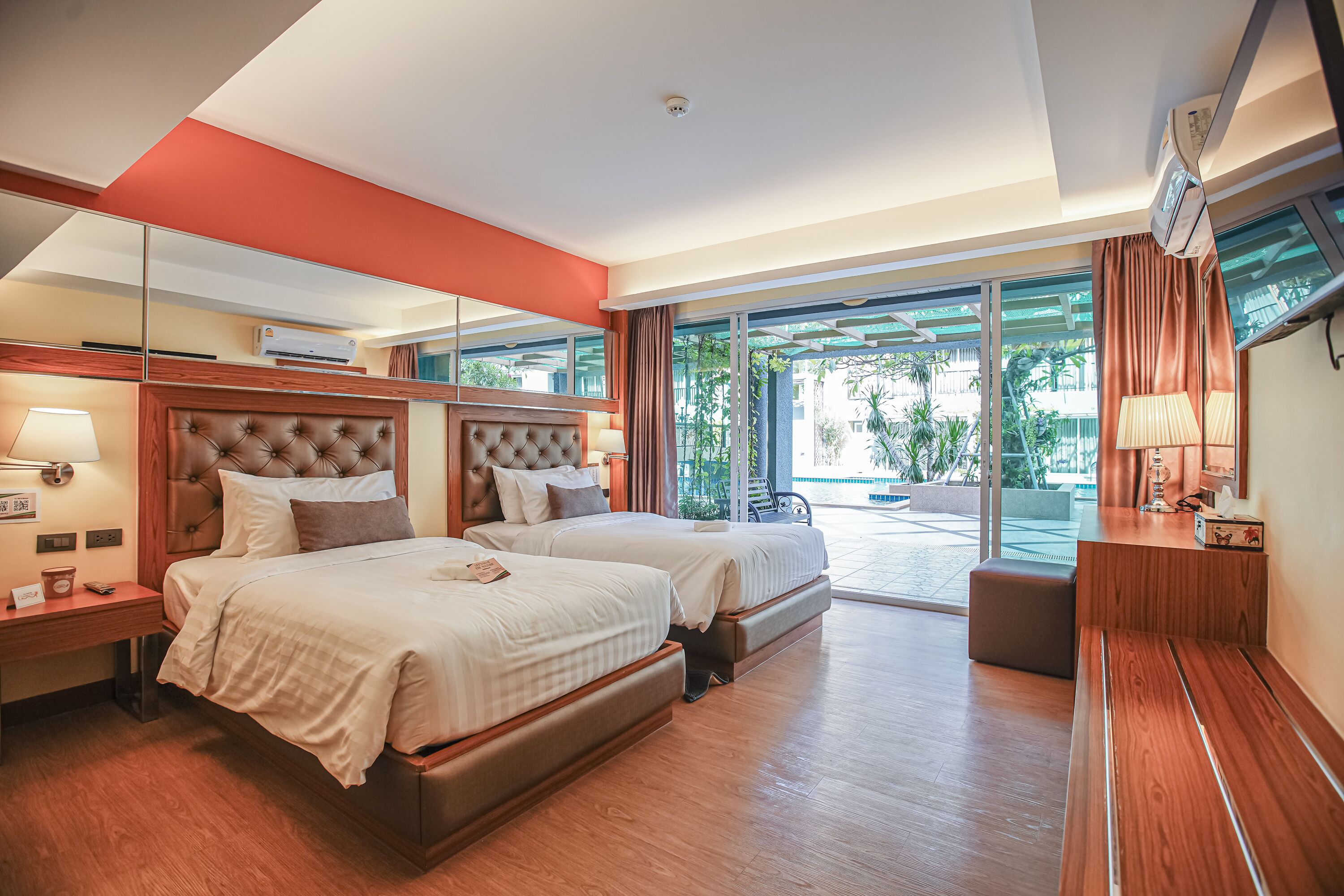 A modern hotel room with two beds, a large window with a view of the outdoors, and a balcony.