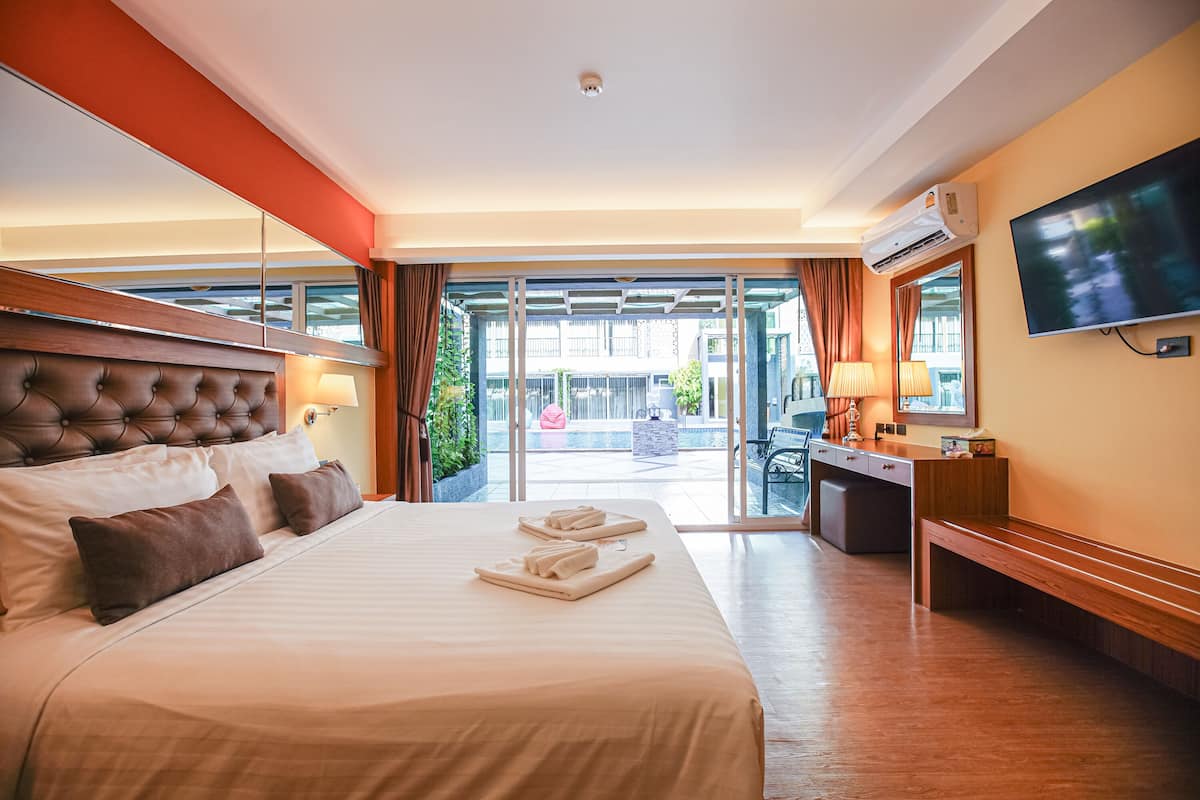 A hotel room with a large bed, a desk, a TV, and a view of the outside.