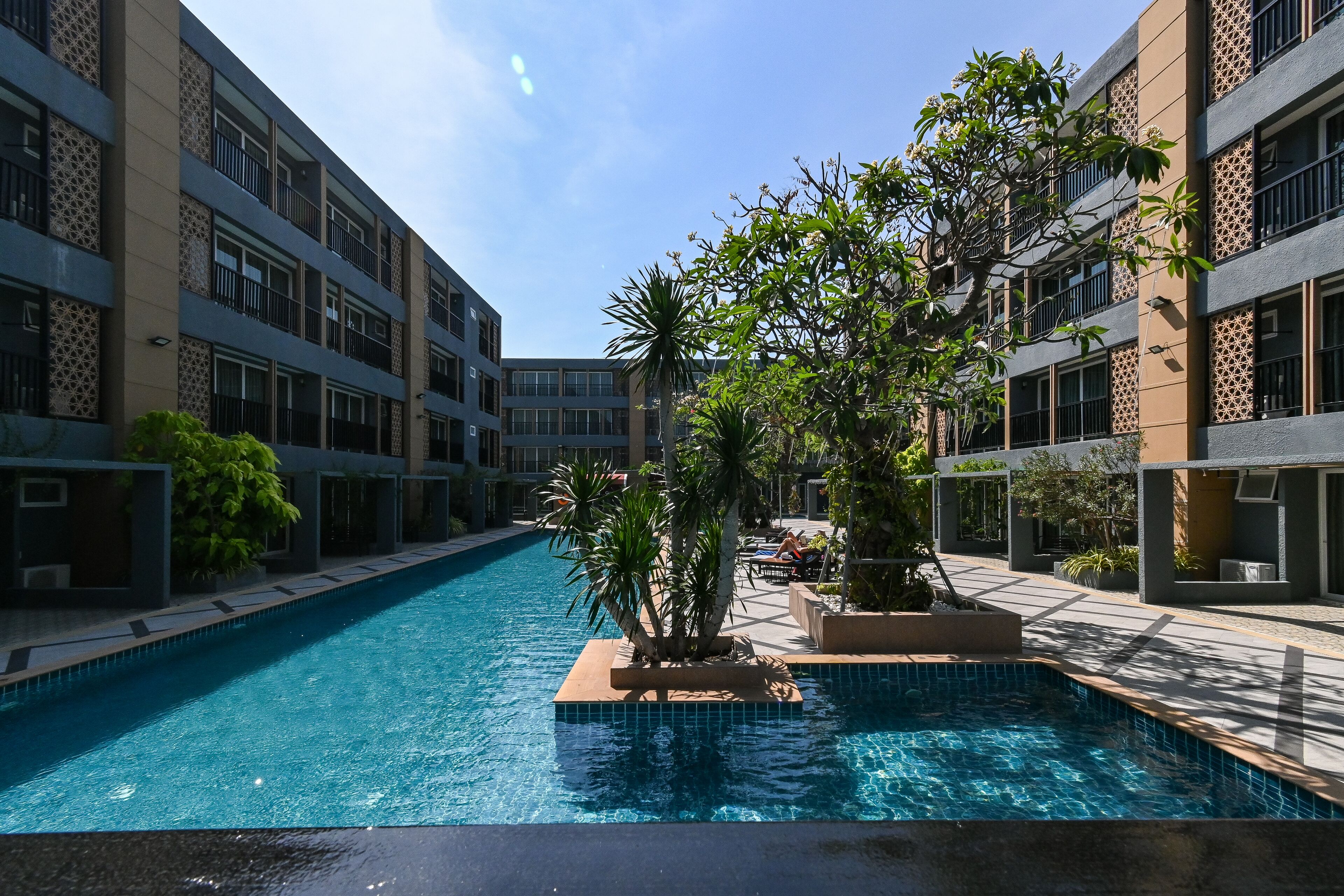 Piscina rodeada por edifícios modernos com varandas e padrões decorativos.