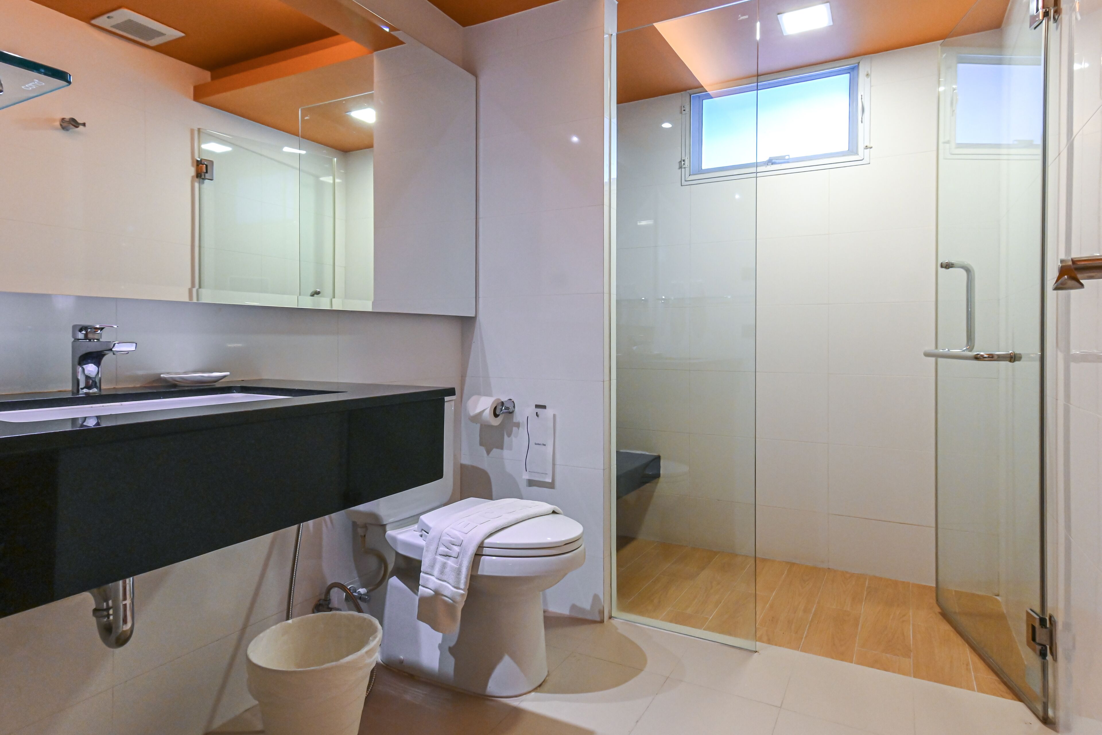 A modern bathroom with a glass shower enclosure, a toilet, and a sink with a black countertop.