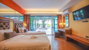Een hotelkamer met twee bedden, een televisie en een balkon met uitzicht op palmbomen.