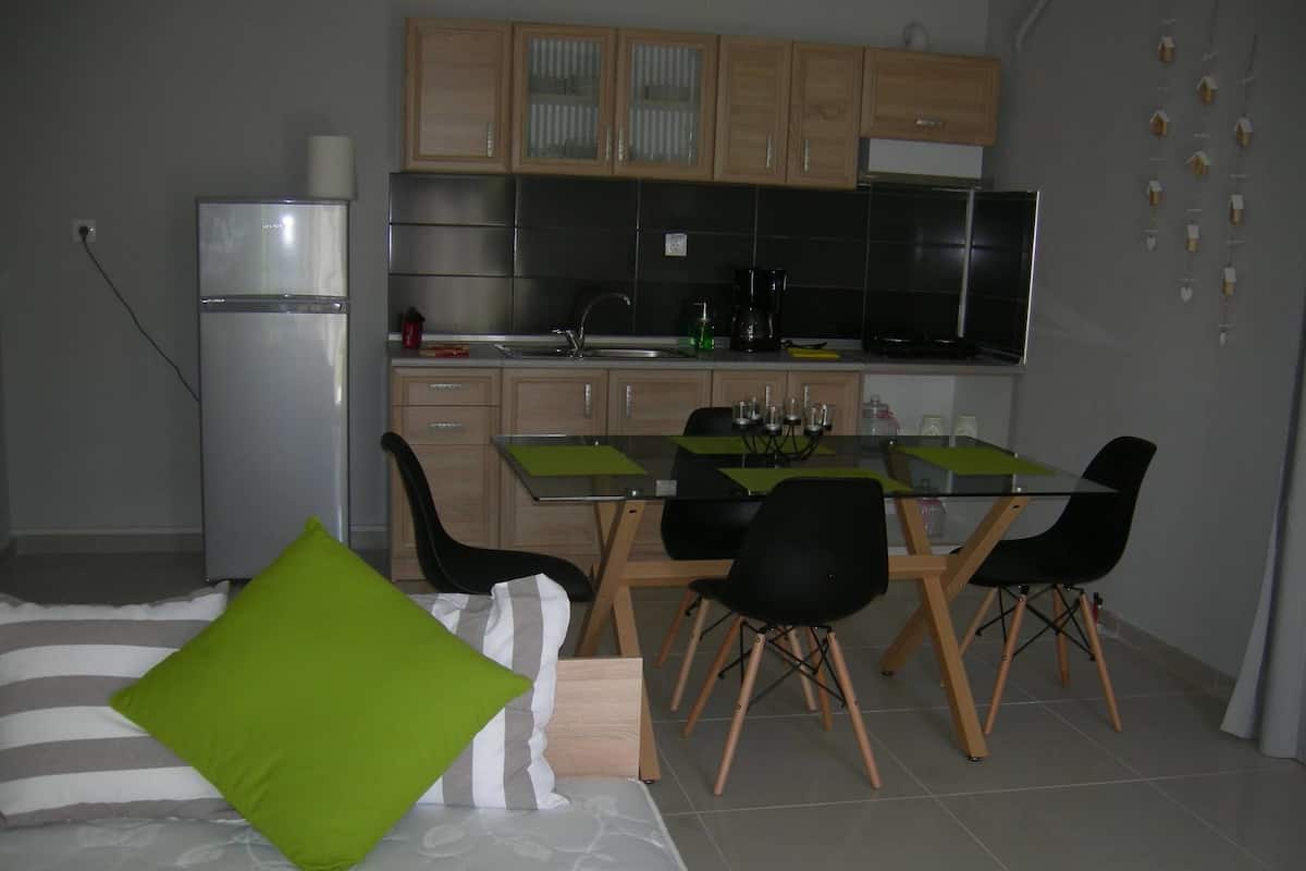 A compact kitchen with a dining table, chairs, and a refrigerator.