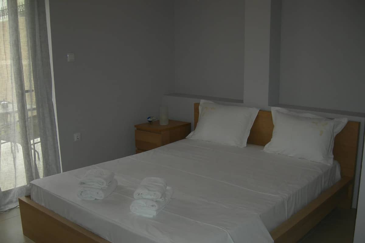 A neatly made bed with white linens and towels, a wooden headboard, and a nightstand with a lamp.
