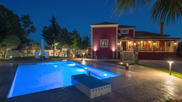 A swimming pool with a hot tub, surrounded by a patio area with outdoor lighting. - Villa Froso (Zakynthos)