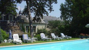 A poolside area with lounge chairs and a building with a dome structure. - Château de Beaulieu (Saumur)