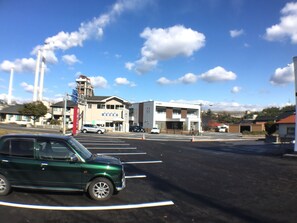 A parking lot with a green car, a building with a sign, and a clear sky.