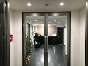 A reception area with a glass door, a reception desk, and a potted plant.