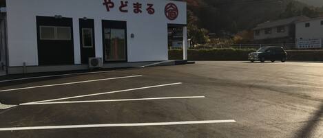A building with a sign reading "やどまる" and a parking lot in front.