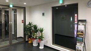 A reception area with a glass door entrance, a large window with a view, and a bulletin board with pamphlets. - Yadomaru Mine Non Smoking (Mine)