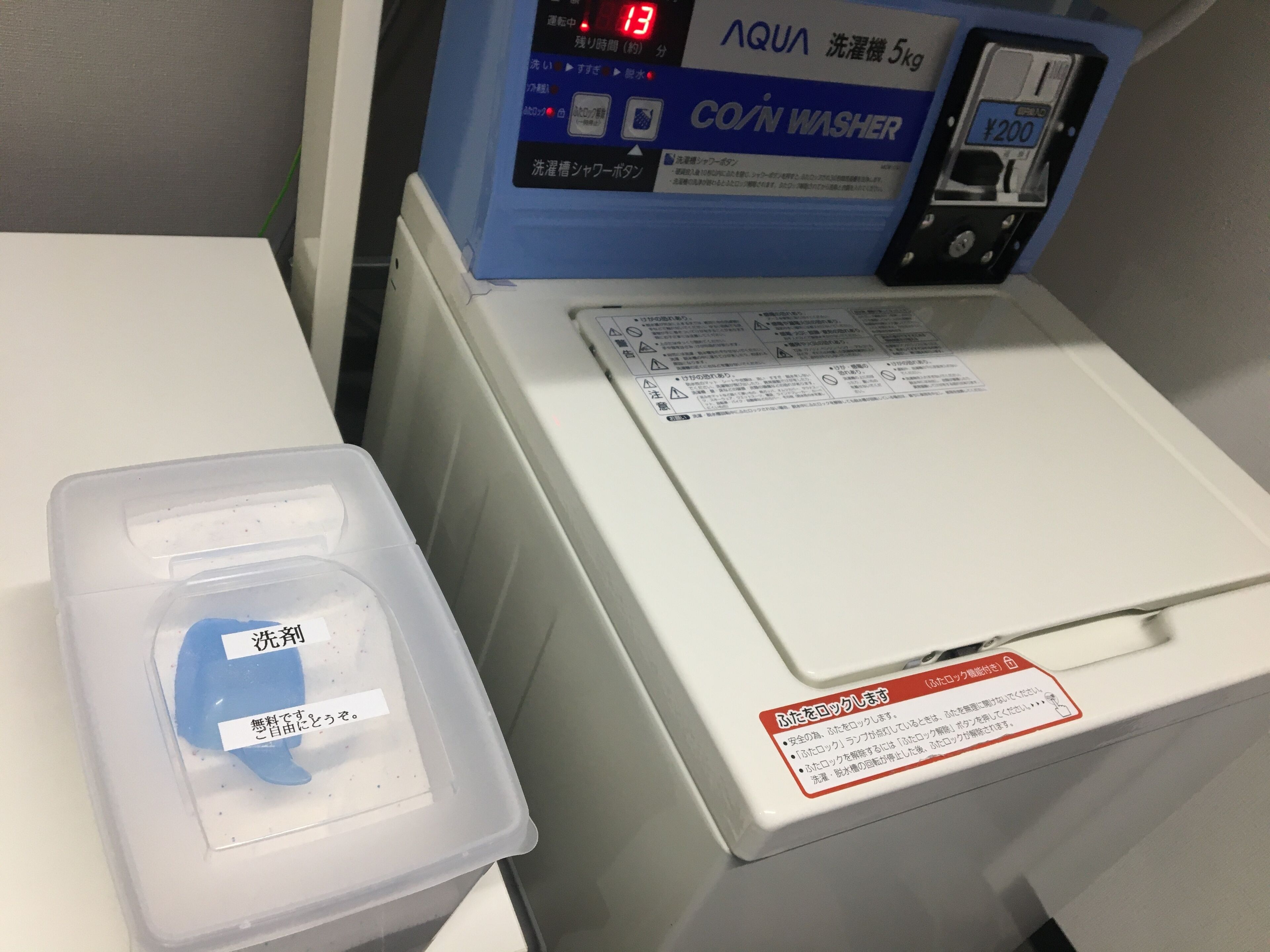 A front-loading washing machine with a control panel displaying various settings and a price tag of ¥200.