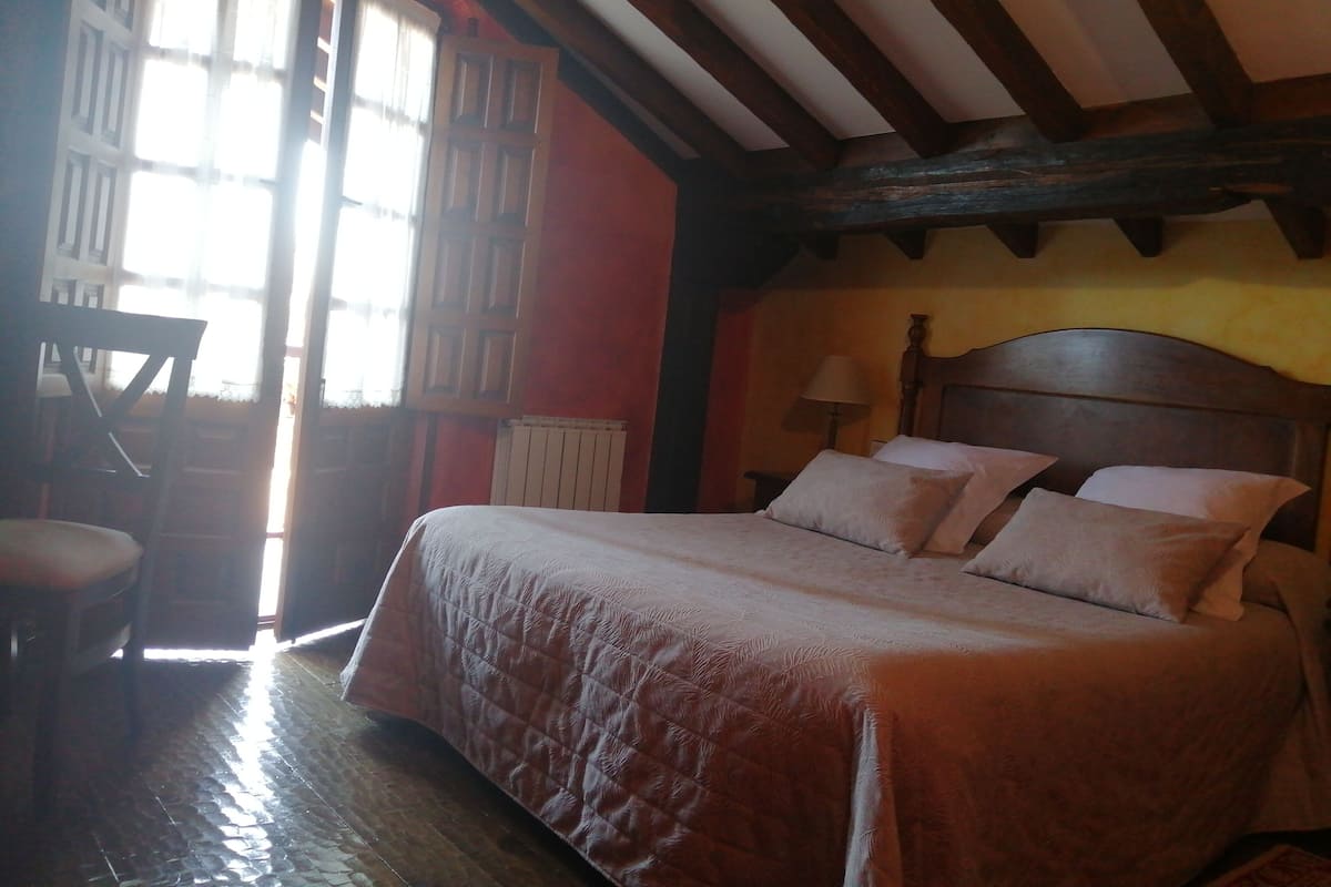 A room with a bed, a chair, a lamp, and a window with curtains.