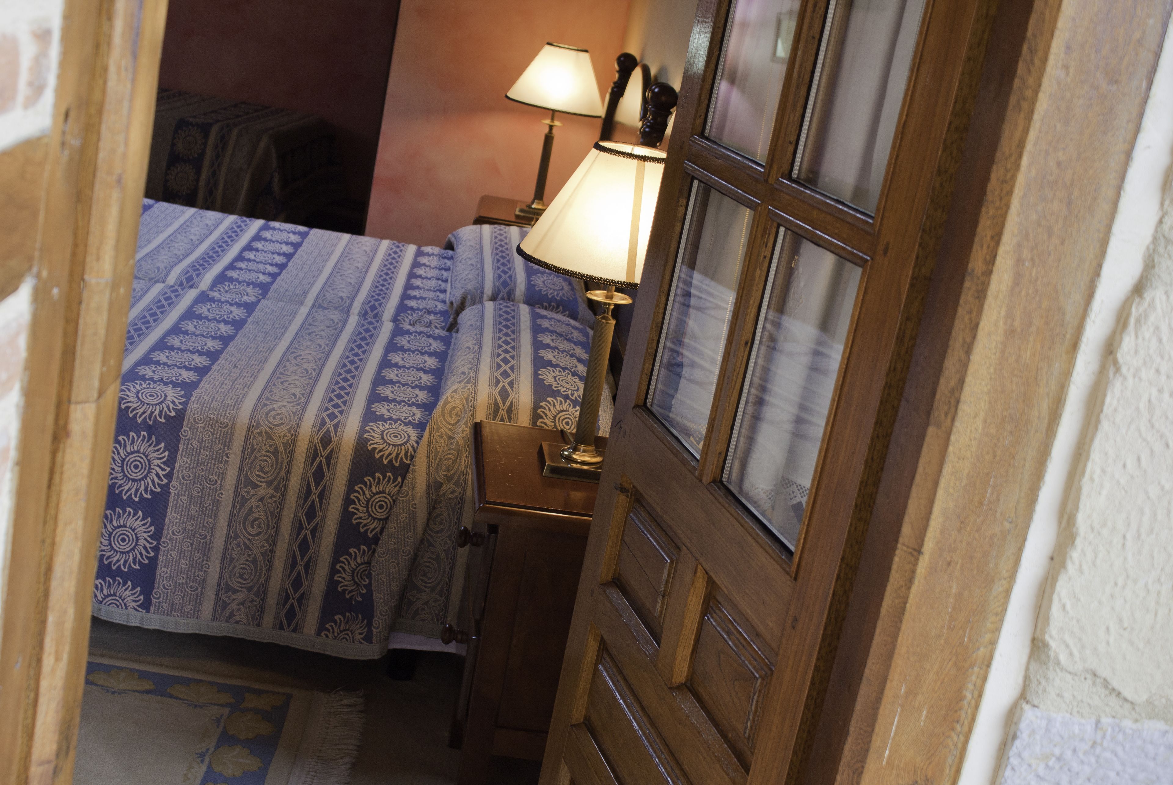 Un dormitorio con una cama, una mesita de noche, una lámpara y una puerta de madera.