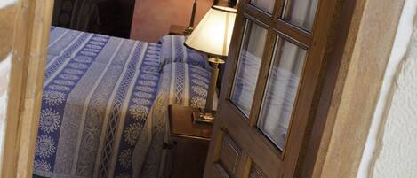 Un dormitorio con una cama, una mesita de noche, una lámpara y una puerta de madera.
