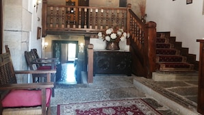 A traditional interior with a wooden staircase, a chandelier, and a floral arrangement. - Posada La Casa del Organista (Santillana del Mar)