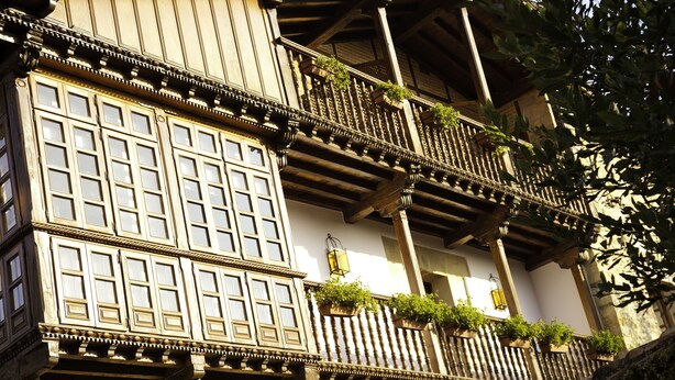 A traditional building with multiple balconies, wooden railings, and potted plants. - Posada La Casa del Organista (Santillana del Mar)