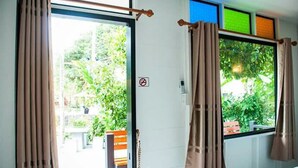 Ein Zimmer mit einer Schiebetür zu einem Außenbereich, einem mit Vorhängen versehenen Fenster und einem Rauchverbotsschild an der Wand.