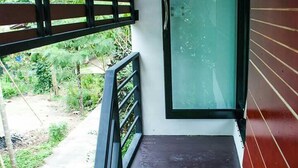 Ein schmaler Balkon mit Glastür und Metallgeländer.