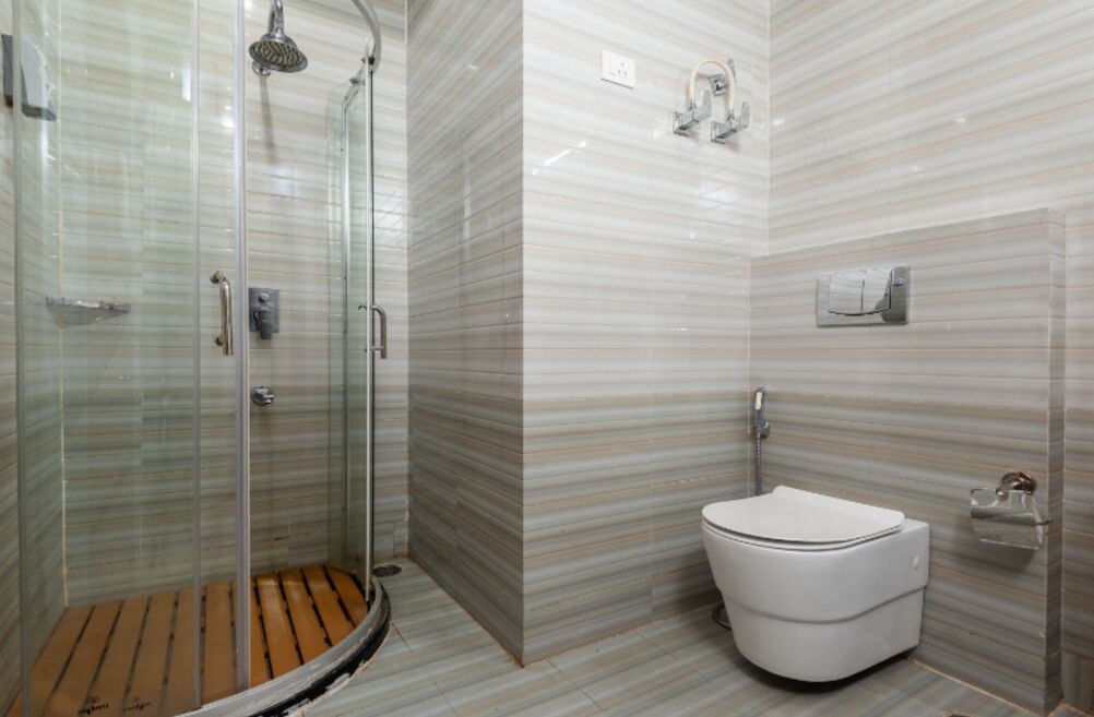 Un baño moderno con ducha de vidrio, inodoro blanco y pared con diseño de mármol.