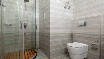 Un baño moderno con ducha de vidrio, inodoro blanco y pared con diseño de mármol.