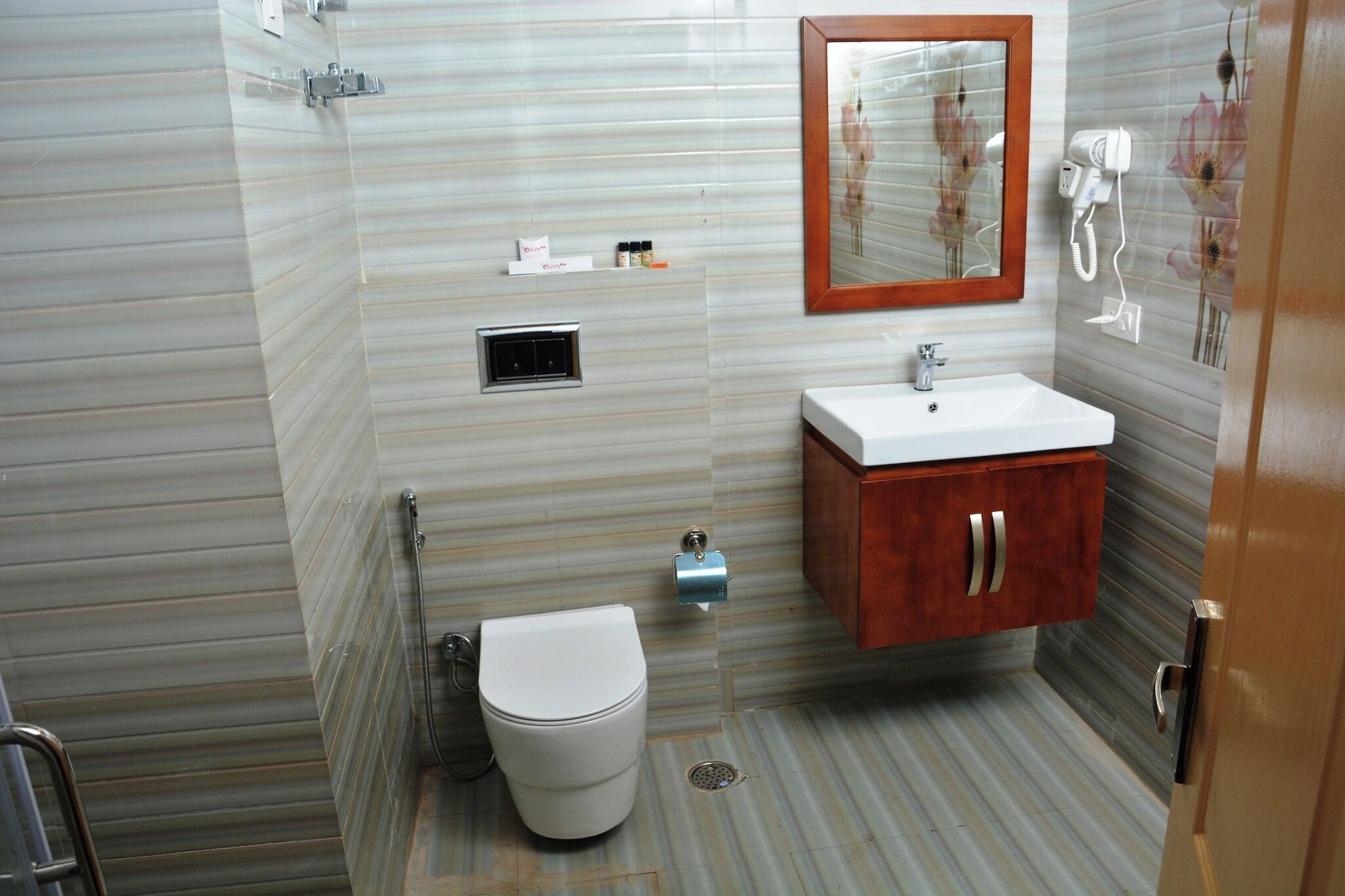 A bathroom with a toilet, sink, mirror, and shower.