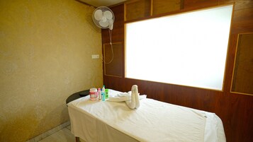 Una habitación con cama, ventana y ventilador.