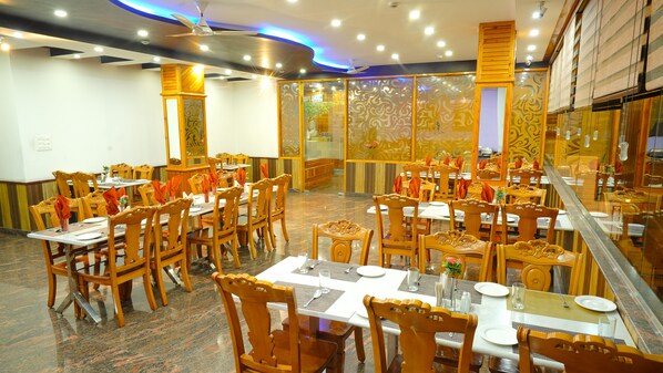 A restaurant with multiple tables and chairs, arranged in a spacious layout. - Hotel Shiva Sanctuary (Dharamshala)